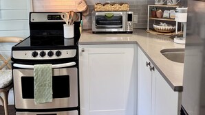 Una cocina moderna con gabinetes blancos, microondas, tostadora y estufa.