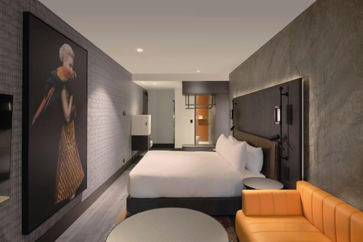 Une chambre d ’hôtel avec un grand lit, un canapé, une télévision et un tableau au mur.