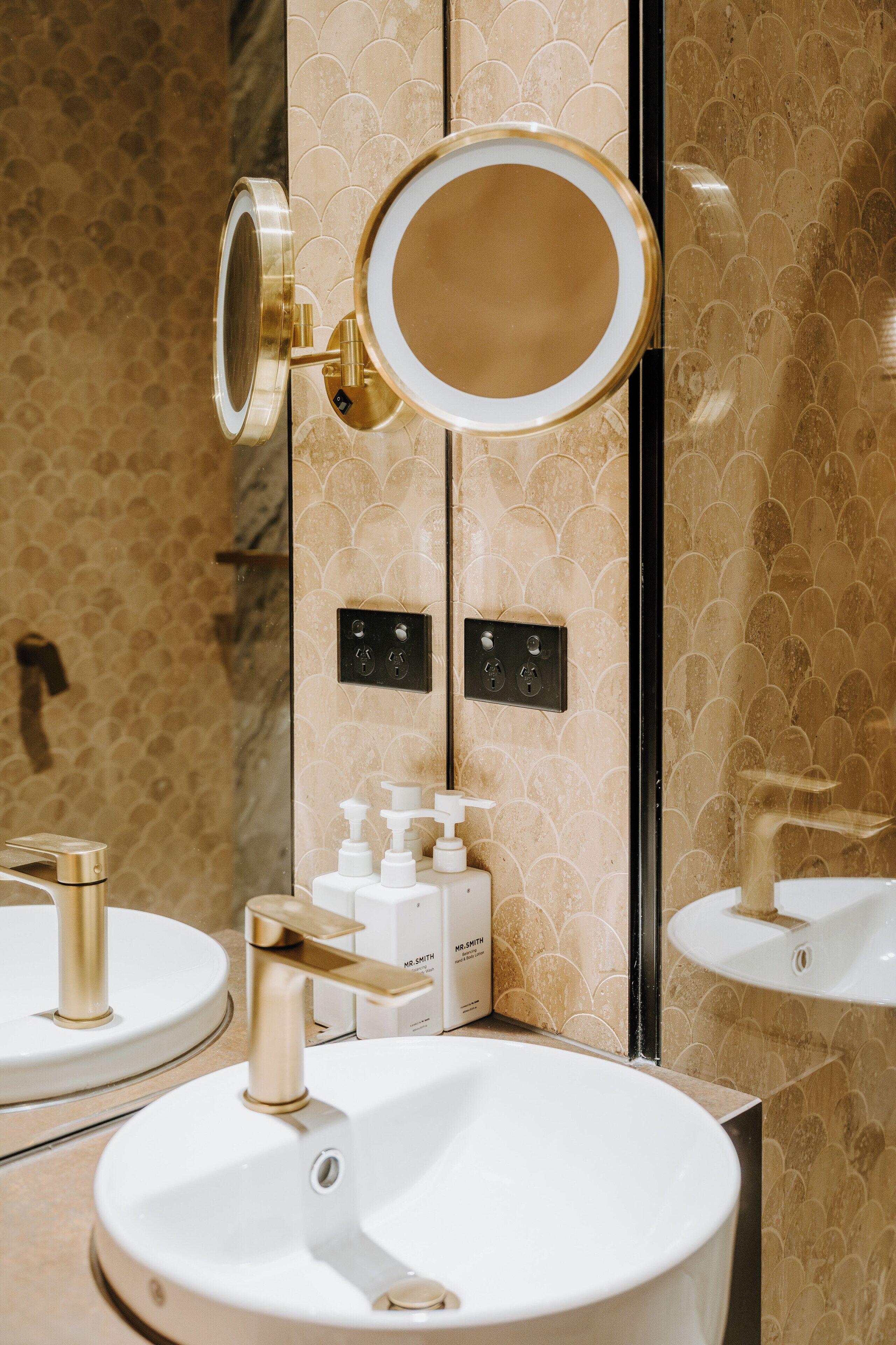 Un baño con dos lavamanos, un espejo y una lámpara en la pared.