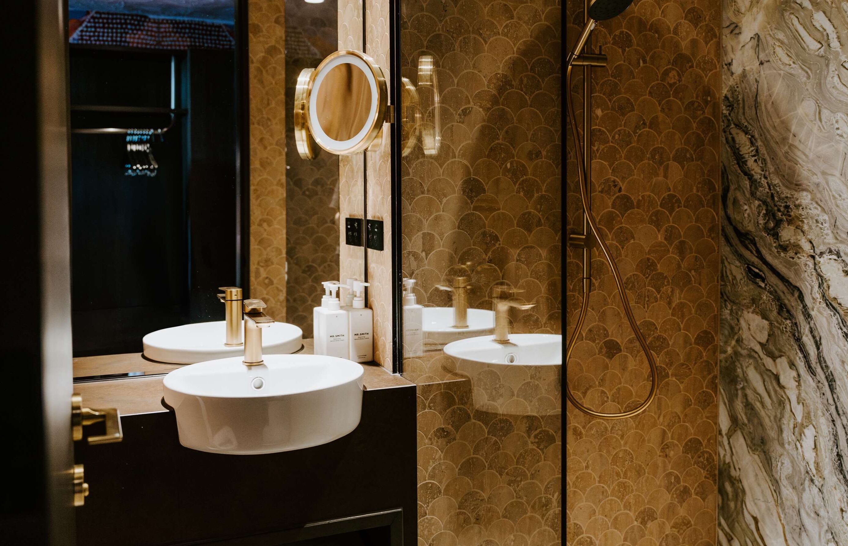 Une salle de bain avec deux lavabos, un miroir et une douche.