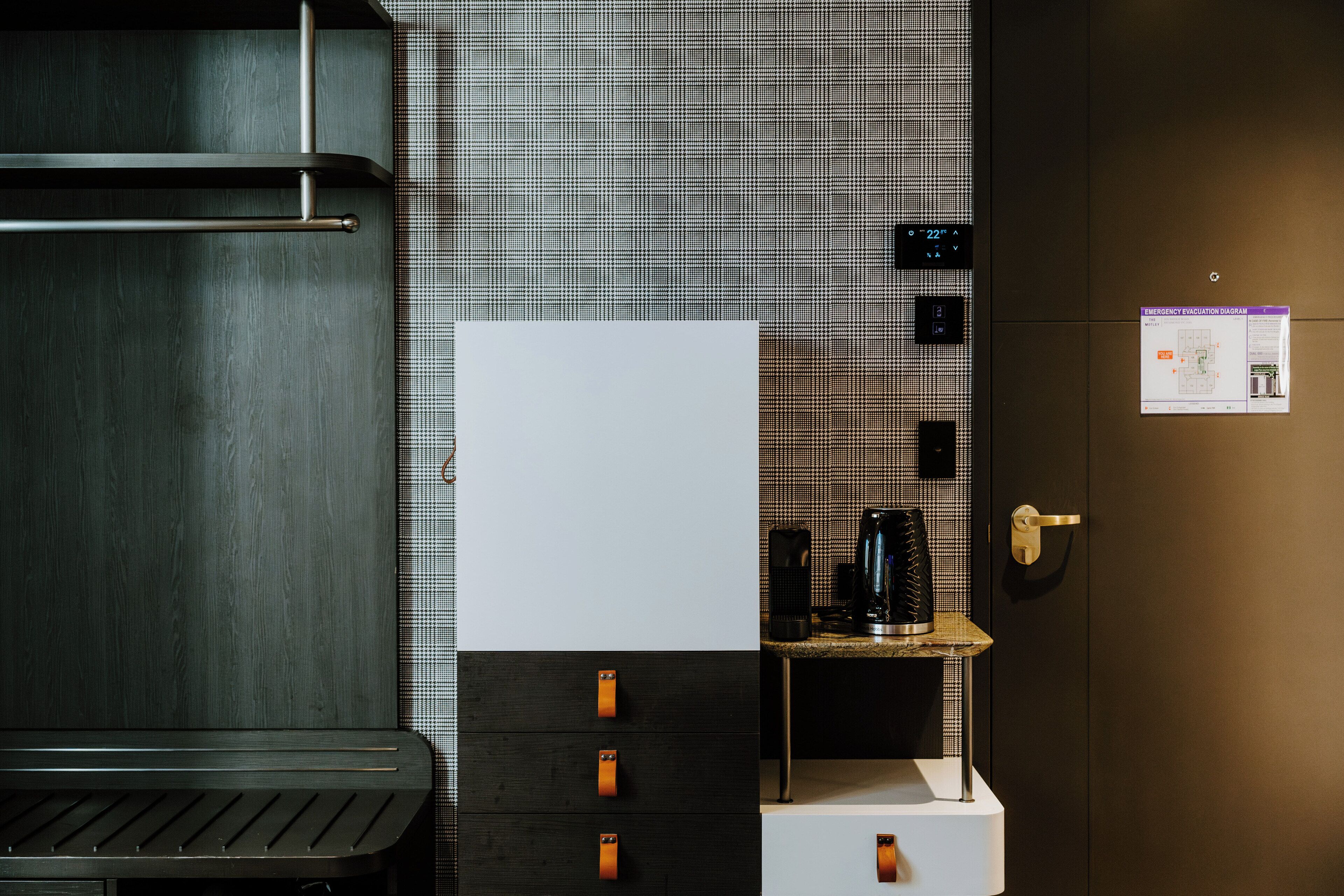 A modern bathroom with a large mirror, a towel rack, a sink, and a coffee machine.
