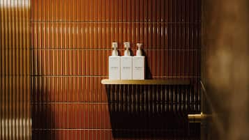 A bathroom with a bamboo-textured wall, a towel rack, and a shelf with three bottles labeled "Mr. Smith."