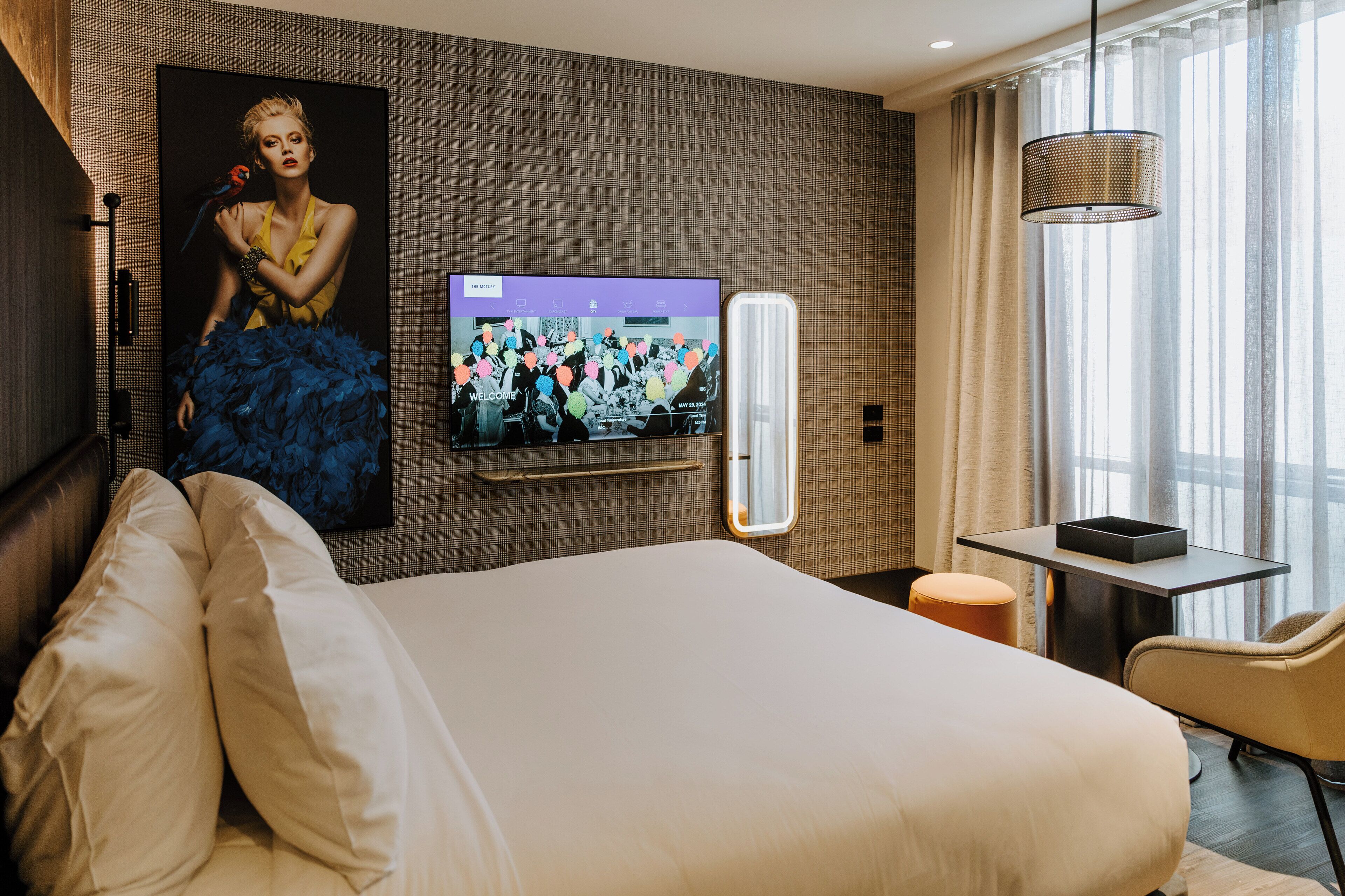A hotel room with a large bed, a flat-screen TV mounted on the wall, a small table, and a chair.