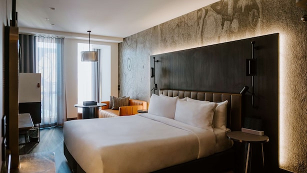Una habitación de hotel moderna con una cama grande, un escritorio y una silla.
