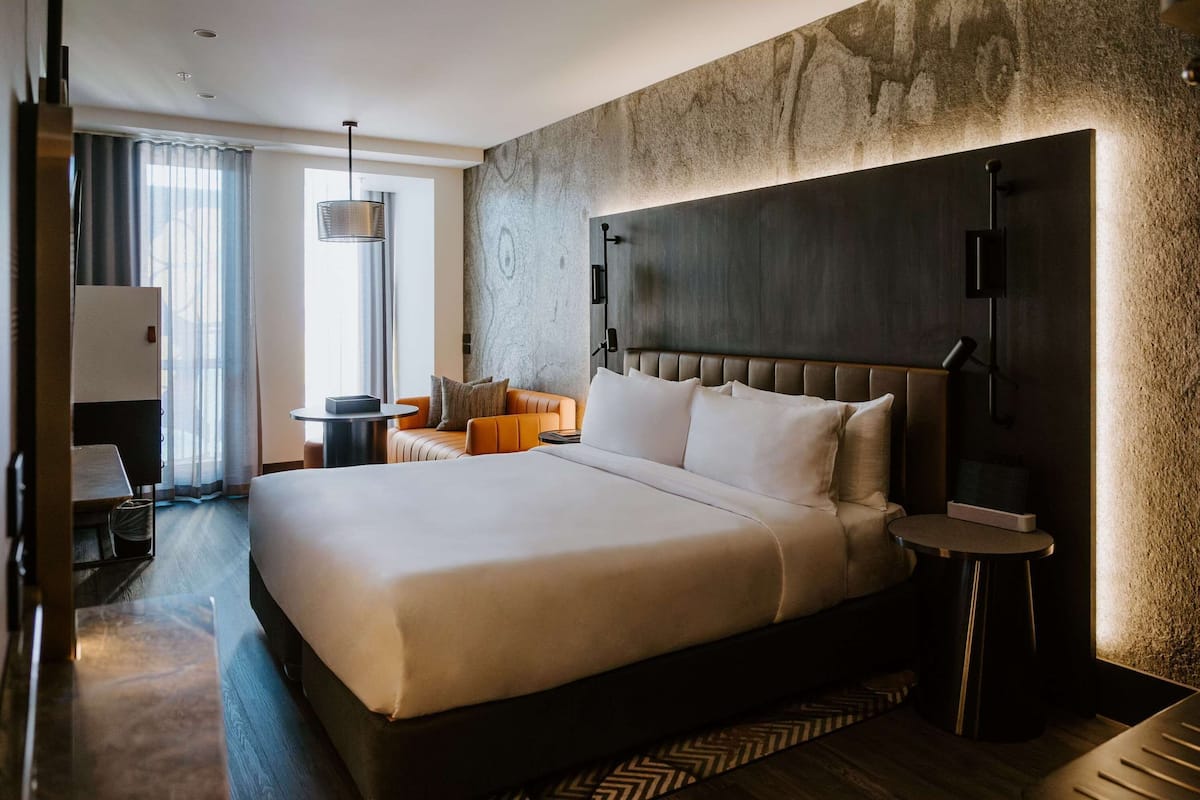 Une chambre d’hôtel moderne, dotée d’un grand lit, d’un bureau et d’une chaise.