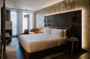 Una habitación de hotel moderna con una cama grande, un escritorio y una silla.