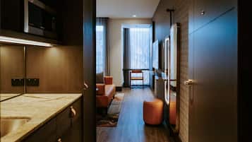Un couloir d’hôtel moderne comprenant un coin cuisine, un espace salon et une grande fenêtre avec des rideaux.