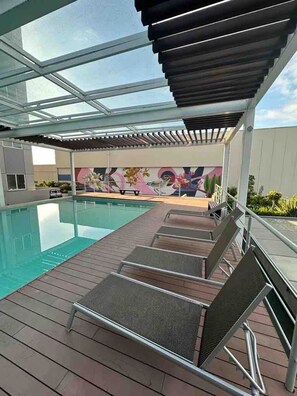 Una piscina interior con cubierta de madera y sillones de descanso.