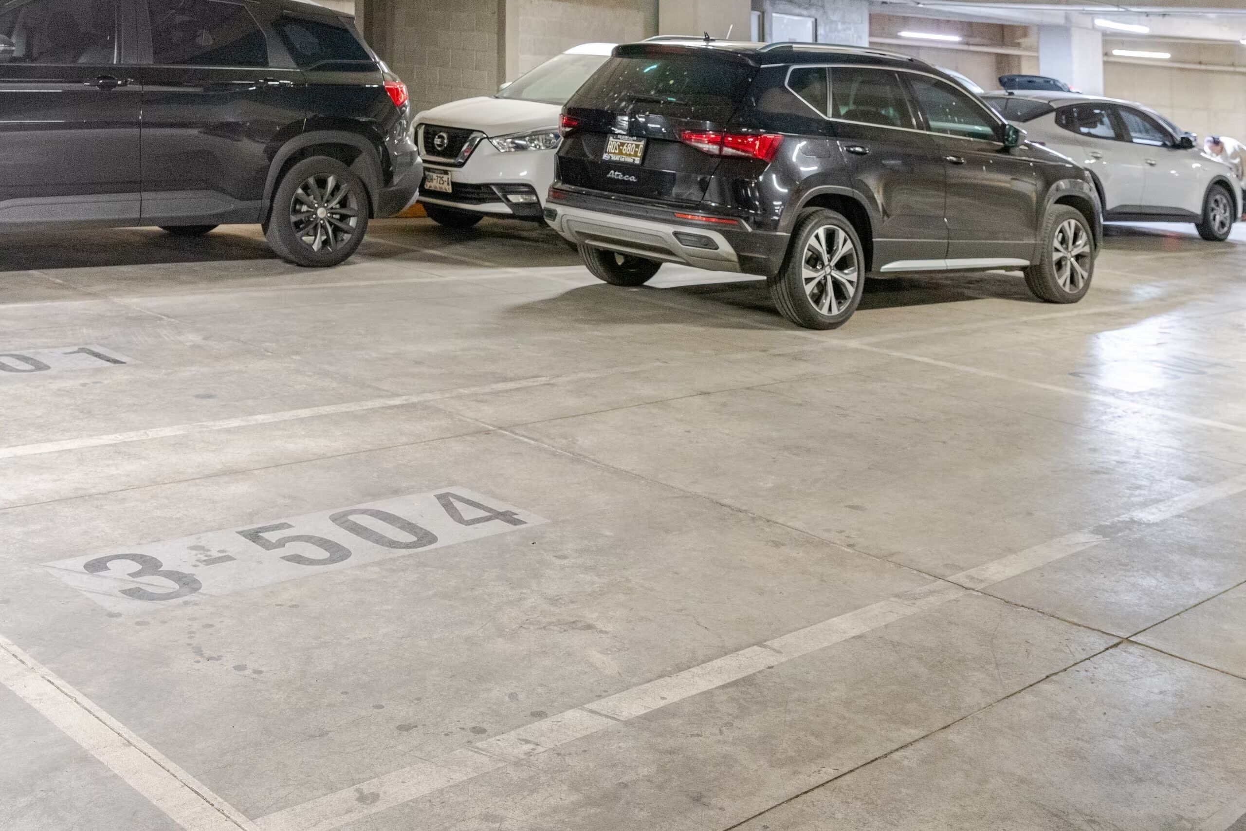 Een parkeergarage met auto's geparkeerd op aangewezen plaatsen, waaronder een plek met nummer 3504.