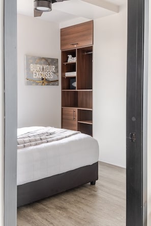Un dormitorio con cama, armario y estante de pared.