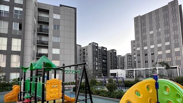Un'area giochi con attrezzature colorate, circondata da moderni palazzi residenziali.