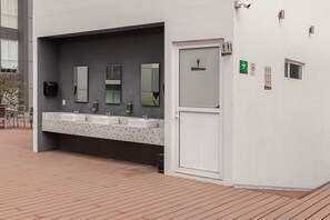A public restroom with three sinks, a mirror, and a door with a gender-specific sign.