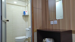 Une salle de bain comprenant des toilettes, une étagère avec des articles de toilette, un miroir et une prise de courant.