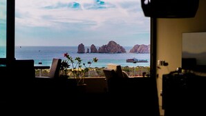 A television screen displaying a coastal view with rocky formations and a ship in the distance. - Fabulous Cabo condo with amazing view of lands end! (Cabo San Lucas)