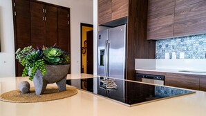 A modern kitchen with a stainless steel refrigerator, wooden cabinets, and a backsplash with blue and white tiles. - Fabulous Cabo condo with amazing view of lands end! (Cabo San Lucas)