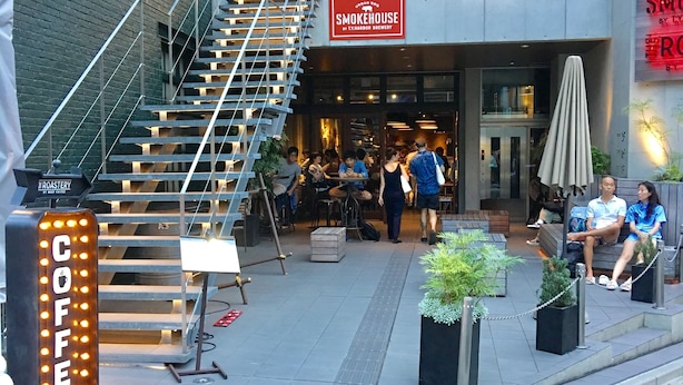 Ein mehrstöckiges Gebäude mit einer Treppe, die zu einer oberen Ebene führt. Ein Schild weist auf Smokehouse BBQ hin und ein Schild auf Kaffee.