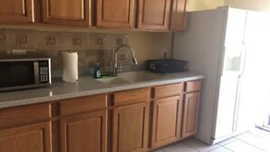 Una cocina con armarios de madera, un microondas, un fregadero y un refrigerador.