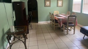 A dining area with a table set for four, a refrigerator, and a television on the wall. - Downtown Sarasota Florida Vacation Rental 3BR/1.5BA House, Near Beaches, Unit 1 (Sarasota)