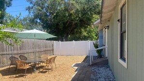 An outdoor patio with a table and chairs, surrounded by a wooden fence and a white railing. - Downtown Sarasota Florida Vacation Rental 3BR/1.5BA House, Near Beaches, Unit 1 (Sarasota)