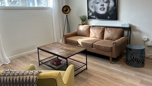 Ein modernes Wohnzimmer mit einer Ledersofa, einem Couchtisch und einem gelben Sessel.