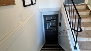 Eine Treppe mit schwarzer Metallreling, eine Tür mit Fensterteil und ein gerahmtes Bild an der Wand.