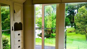 A bedroom with a large bed, a wardrobe, and a sliding glass door leading to a garden.