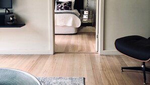 A bedroom with a bed, bedside table, lamp, and a TV on a stand.