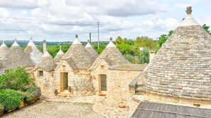 A row of stone-roofed buildings with small windows and doors, surrounded by greenery.