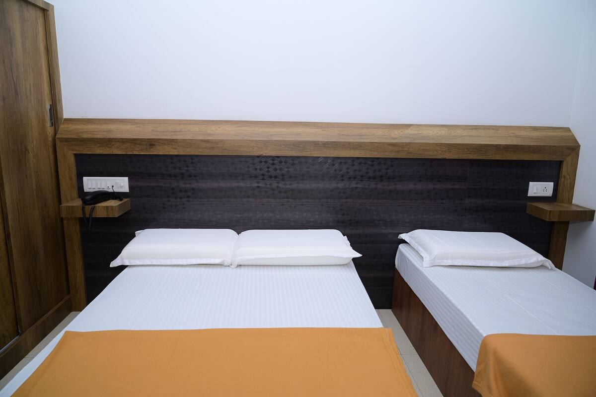 A hotel room with two beds, wooden headboards, and a dark wall.