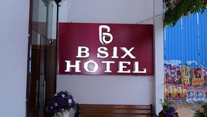 The entrance of B6X Hotel with a red carpet, a large sign, and two flower arrangements. - B SIX HOTEL AND LODGE (Bengaluru)