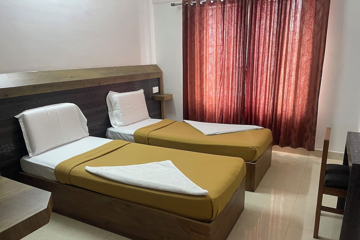 A hotel room with two beds, a wooden headboard, a nightstand, a desk, and a chair.