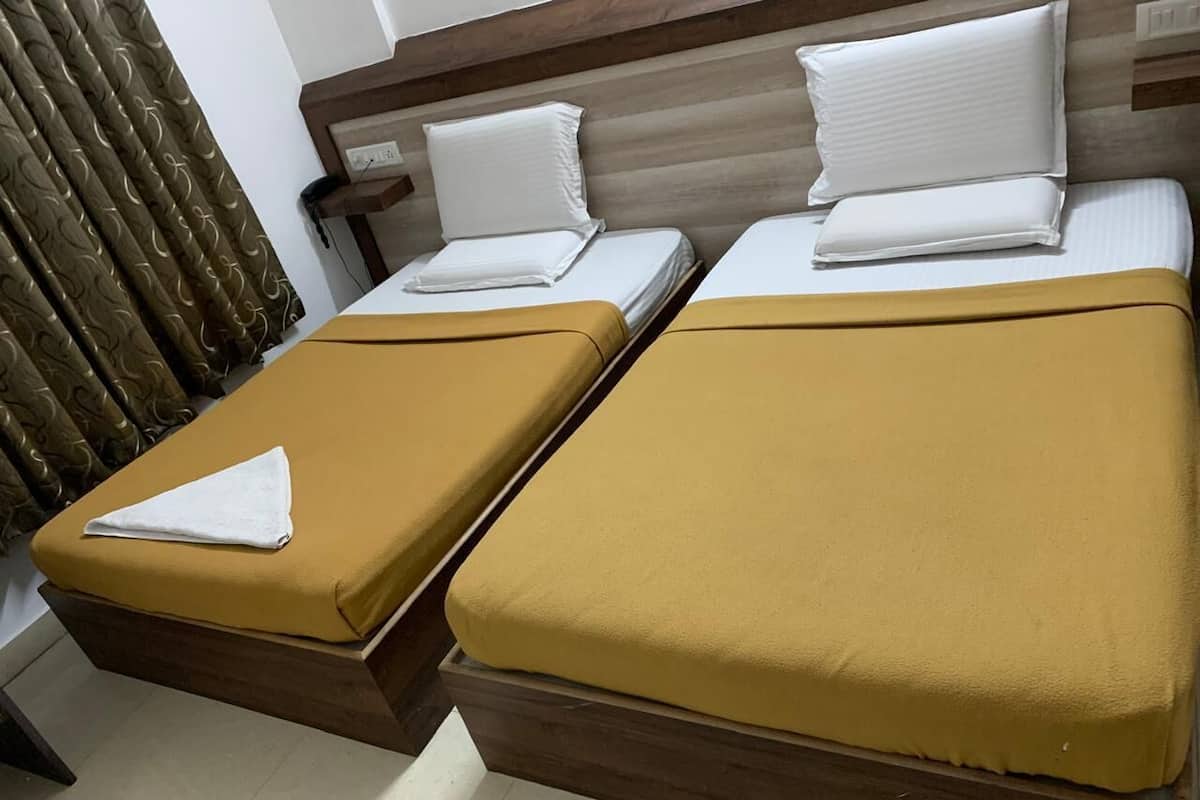 A double bed with a wooden headboard and two pillows, a single bed with a wooden headboard and a pillow, and a brown curtain.