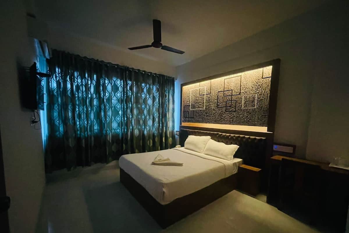 A bedroom with a bed, a ceiling fan, a TV, and a patterned wall.