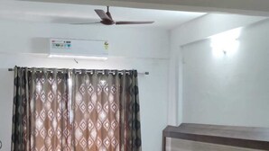 A hotel room with a large bed, a smaller bed, a ceiling fan, and a window with patterned curtains. - B SIX HOTEL AND LODGE (Bengaluru)