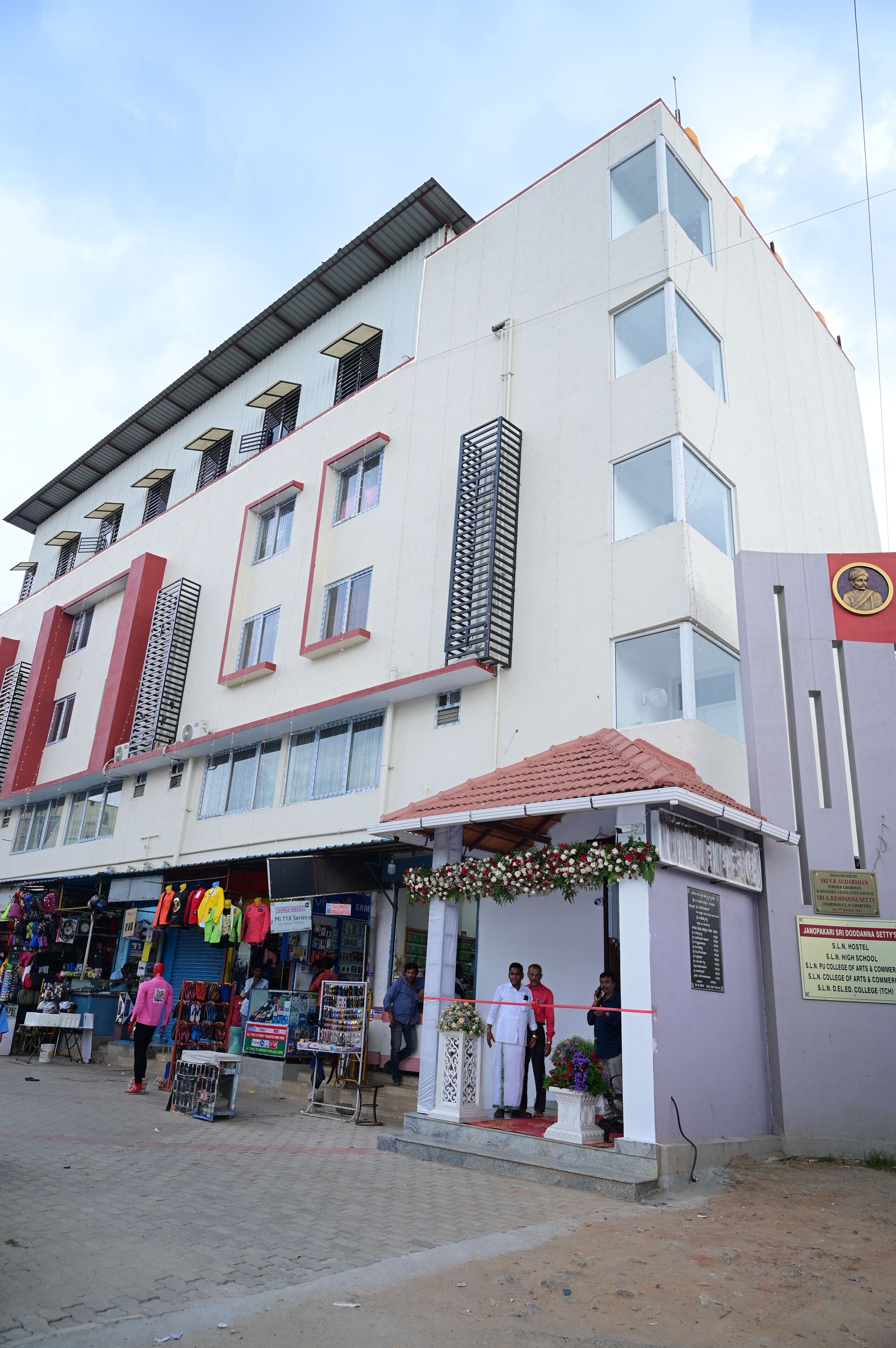 A multi-story building with a flat roof, large windows, and a signboard on the right side.
