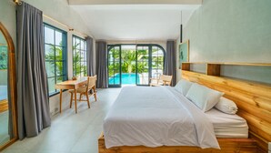 A modern bedroom with a large bed, a wooden headboard, a desk with a chair, and a view of a swimming pool through large windows. - Villa Mellow (Canggu)