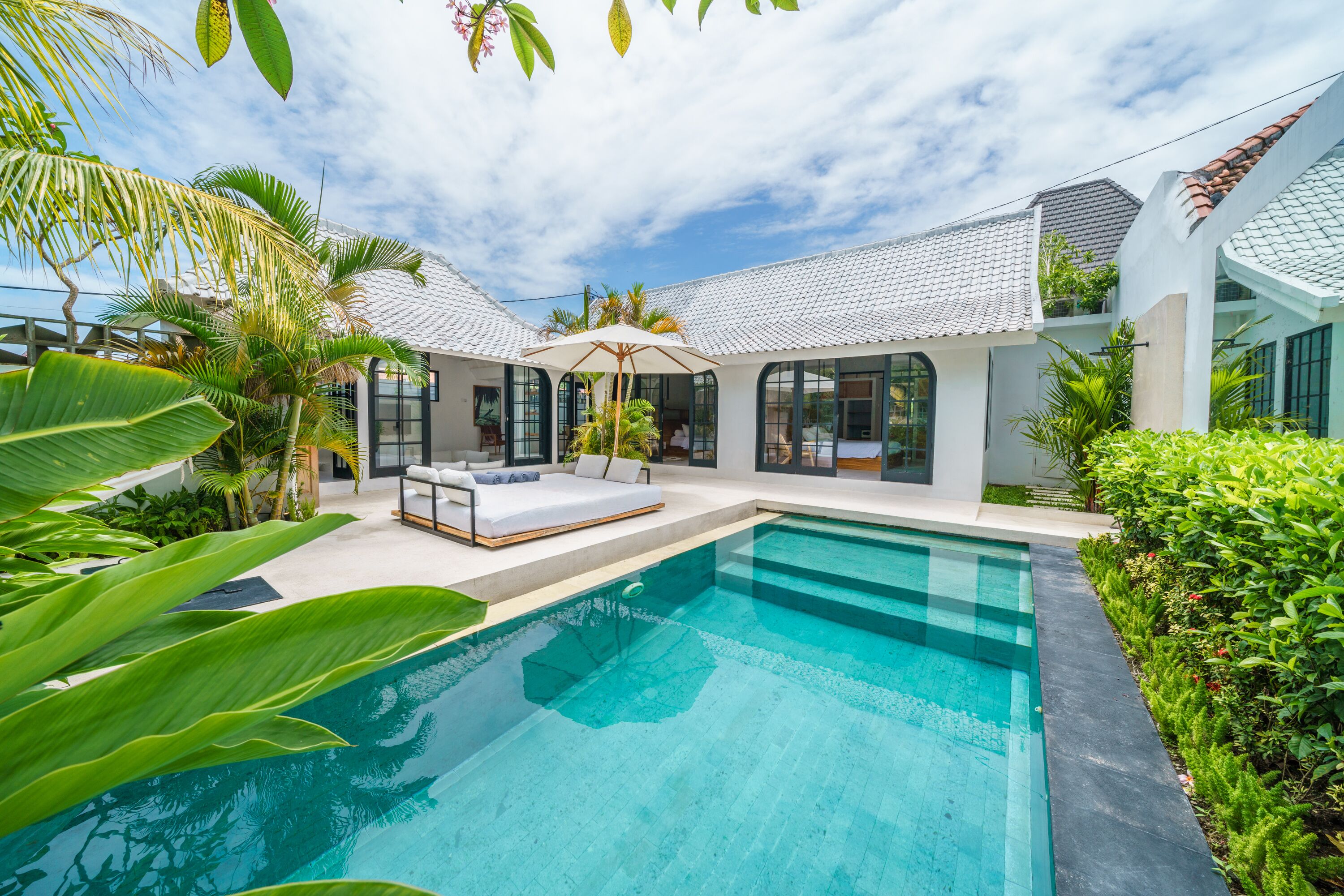 A modern house with a swimming pool, outdoor seating, and lush greenery.