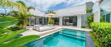 A modern house with a swimming pool, outdoor seating, and lush greenery.