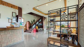 A reception area with a counter, a staircase, and a bookshelf with various items.
