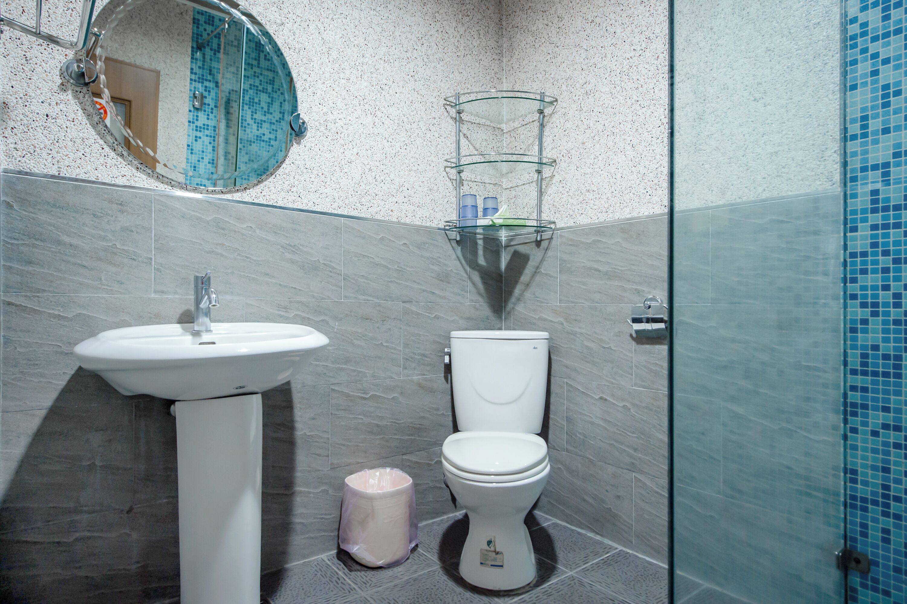 Une salle de bain avec un lavabo sur colonne, des toilettes et une douche à parois de verre.