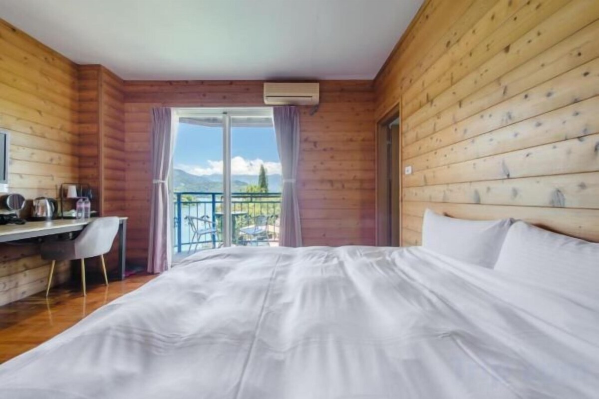 Un dormitorio con cama, escritorio y vista a un balcón.