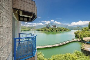 A view from a balcony overlooking a lake with a bridge, buildings on an island, and mountains in the background. - Bishui Shanju Lakeside B&B (Yuchi)