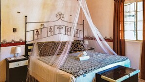 Een bed met hemel, een nachtkastje en een bijzettafeltje.