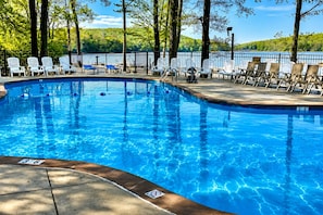 A swimming pool with lounge chairs and a view of a lake.