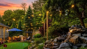 Um campo de golfe com putting green, cadeira de balanço e cascata de pedra.