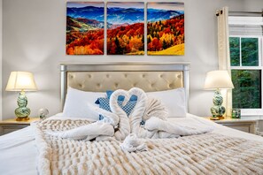 A hotel room with a bed, two nightstands, a window, and three paintings on the wall.