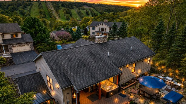 Una casa grande con terraza, jacuzzi y un pequeño campo de práctica de golf.
