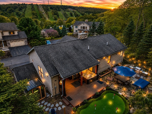 A large house with a deck, a hot tub, and a small putting green.