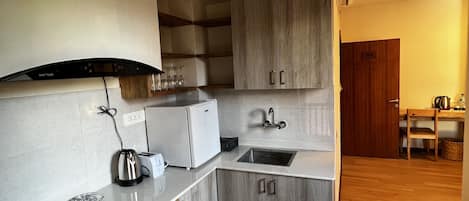 A compact kitchen with a built-in oven, a sink, and wooden cabinets.