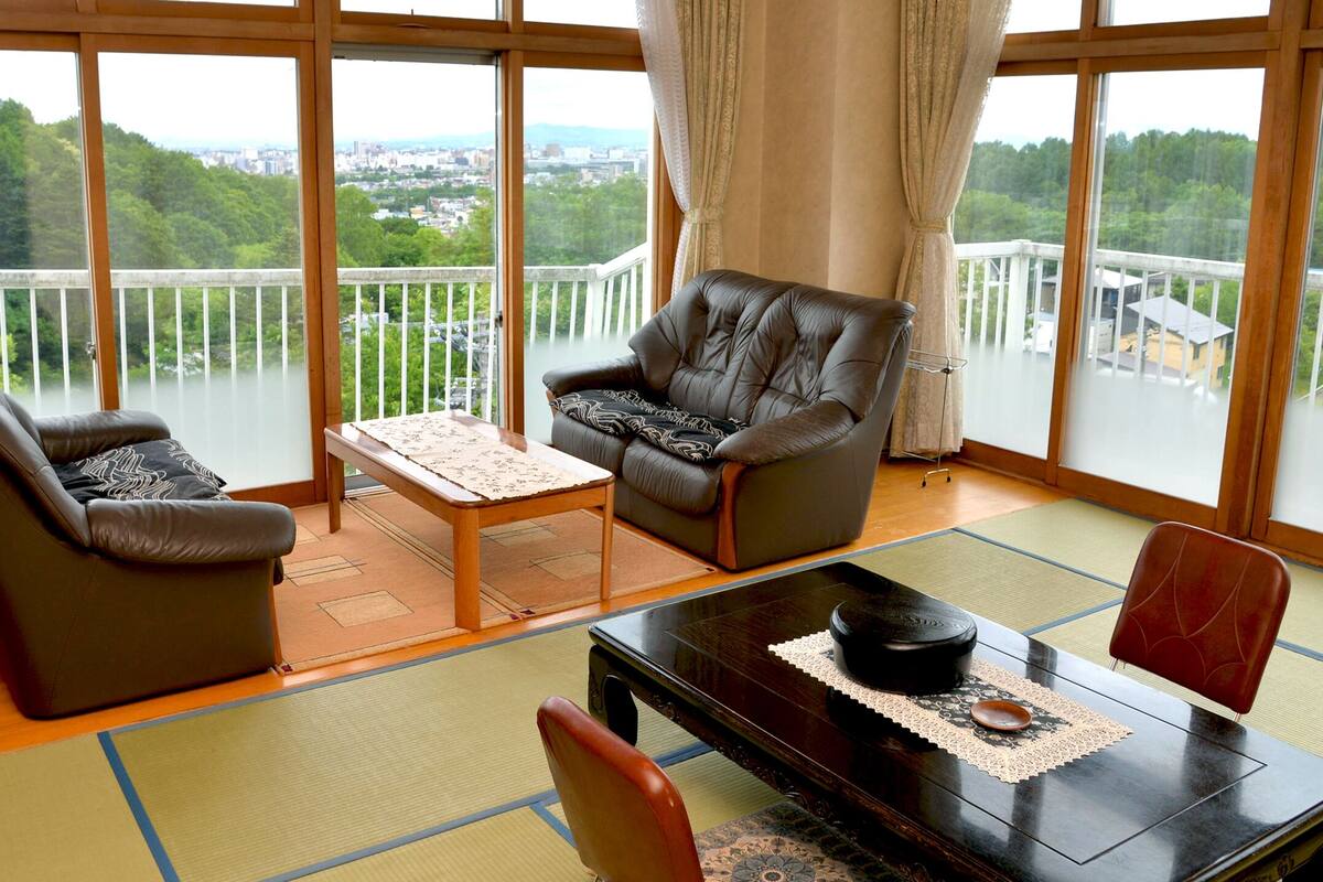 A room with tatami flooring, a low table with a tea set, and a sofa.